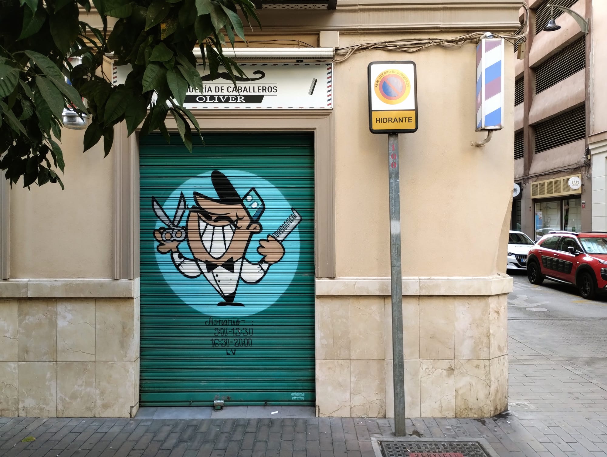 A teal, rolled metal storefront with a colourful illustration of a cartoon barber holding scissors and a comb within a turquoise circle.