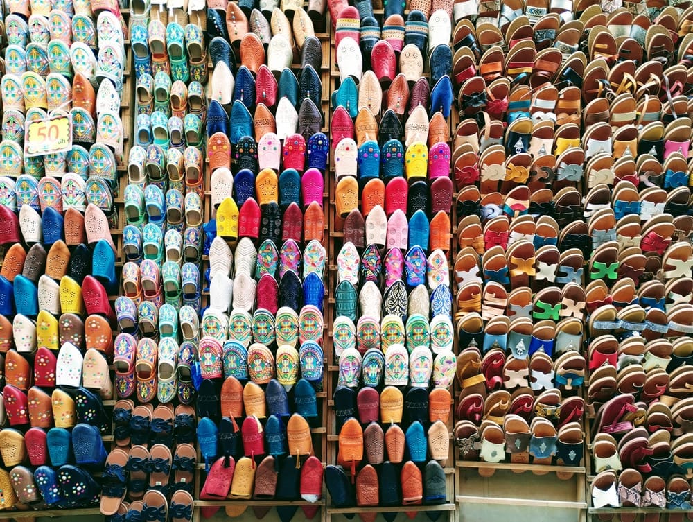Rows of colourful leather slippers and sandals displayed for sale in a market.