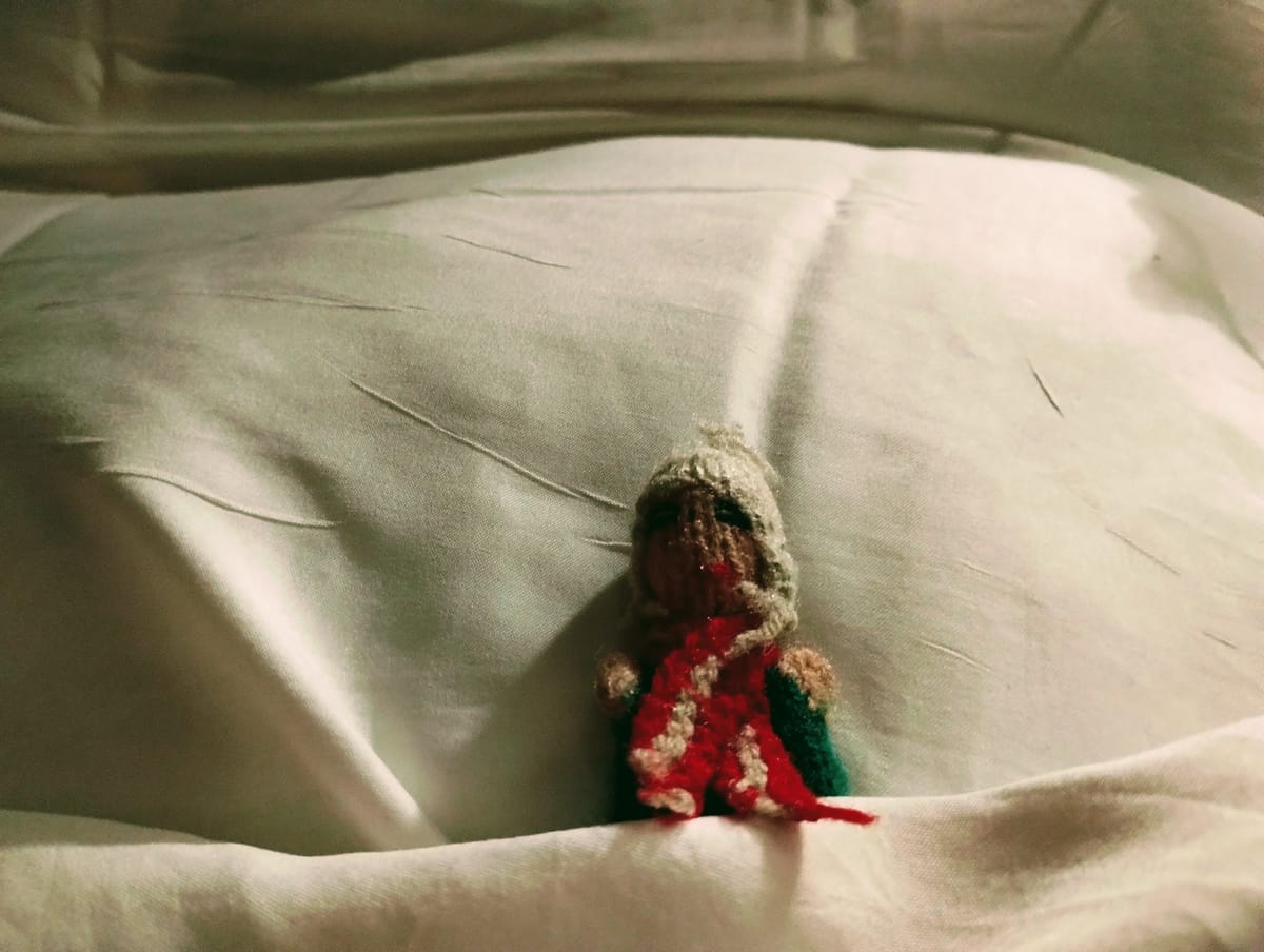 The featured image shows a Peruvian finger puppet lying against a pillow with a sheet pulled up over him.