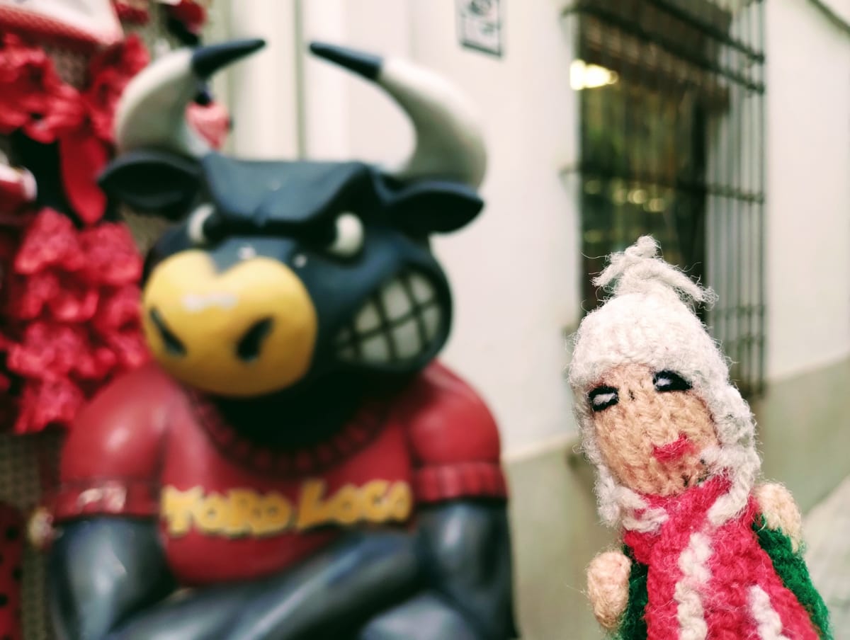 A brave little Peruvian finger puppet in front of a menacing bull with the words "Toro Loco" on its shirt.