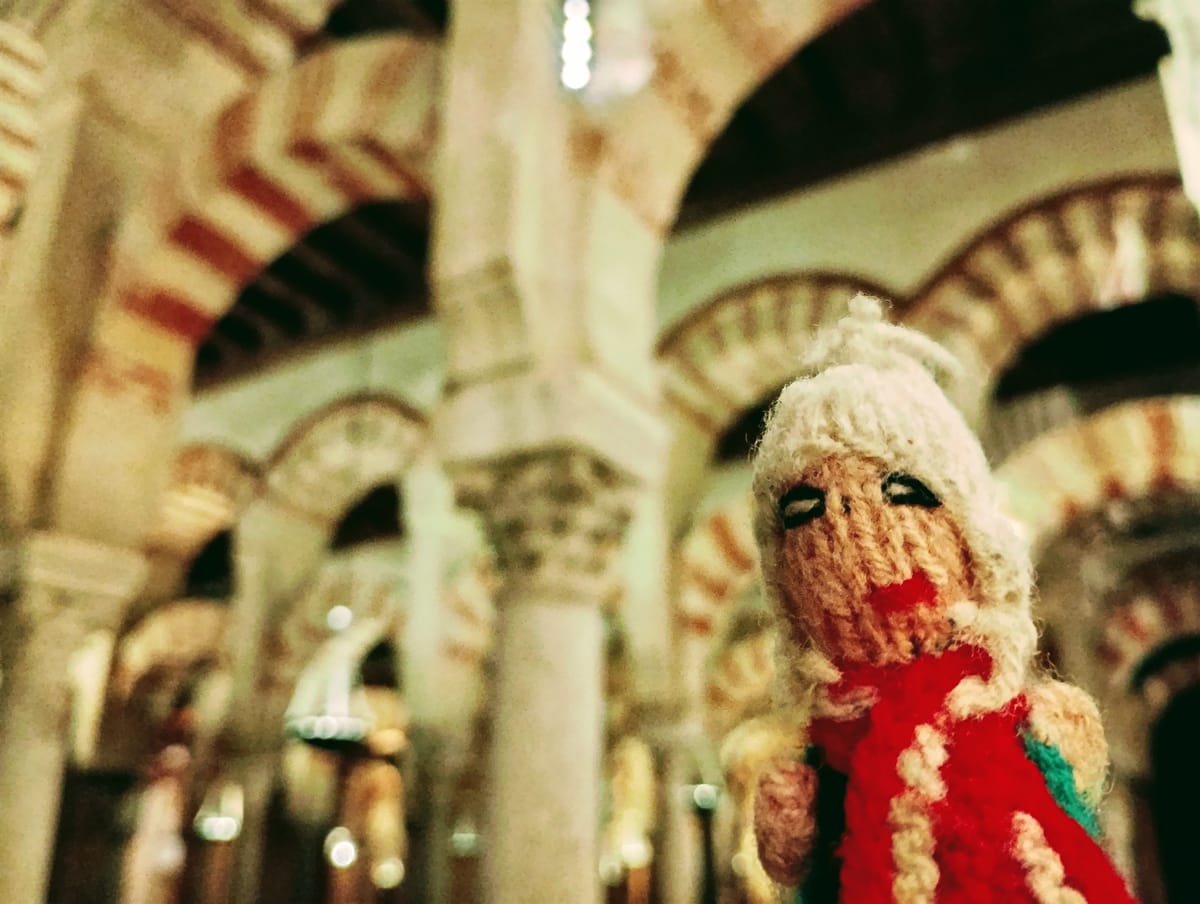 Finger Puppet against the red and white arches and marble columns of the Mezquita-Catedral in Córdoba.